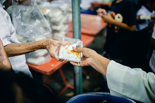 Feeding Concepts . Hand offered to donate food from a rich man Share. The concept of social sharing . Poor people receiving food from donations photo