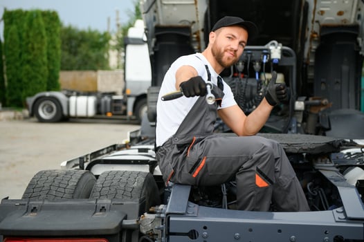 Semi Truck Under Maintenance. Caucasian Truck Mechanic Working to Fix the Tractor. photo