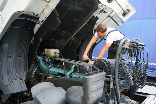 Semi Truck Under Maintenance. Caucasian Truck Mechanic Working to Fix the Tractor. photo