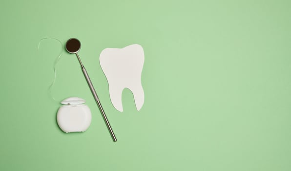 Dental floss and paper teeth on green background, oral hygiene photo