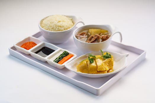 Boneless Hainanese Chicken Rice with chicken soup, soy sauce, chili sauce served in bowl isolated on wooden table side view of hong kong fast food photo