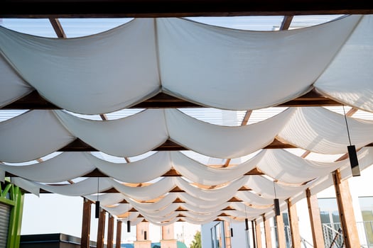 Patio made of white fabric on the roof, the design of an outdoor restaurant in the open air, the protection of cafe visitors in the summer heat, a place to relax in the shade. photo