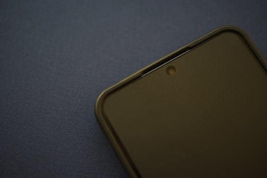 A black smartphone on a blue background. A new gadget. A smartphone with a protective film and a case. photo