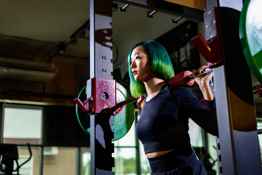 Asian muscular sport woman is practice weight training on deadlift barbell for core muscle inside gym with dark background for exercising and workout photo