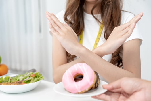 Diet and dieting. Beauty slim female body confuse donut. Woman in exercise clothes achieves weight loss goal for healthy life, crazy about thinness, thin waist, nutritionist. photo