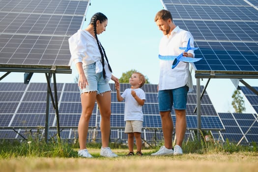 Young family of three is crouching near photovoltaic solar panel, little boy and parents. modern family concept. The concept of green energy photo