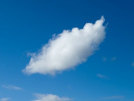 Single white fluffy cumulus cloud in the blue summer sky photo