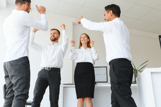 Happy successful multiracial business team giving a high fives gesture as they laugh and cheer their success. photo