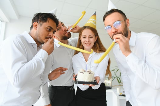 Happy businesswoman holding Birthday cake while making surprise party with her colleagues in the office. photo