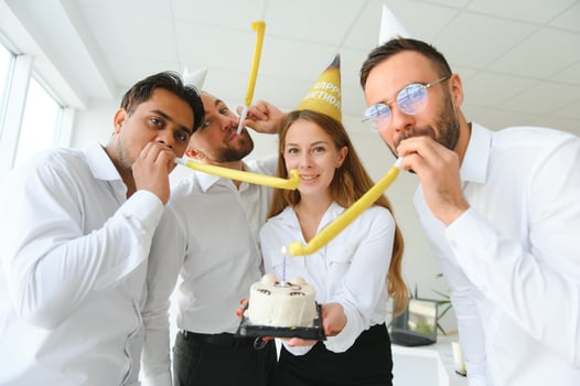 Happy businesswoman holding Birthday cake while making surprise party with her colleagues in the office. photo