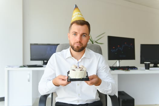 Sad young businessman celebrating birthday alone in office photo