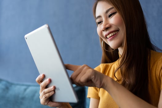 Portrait of Young attractive asian woman resting on sofa and using and looking at tablet pc in modern room communication and lifestyle concept. reading digital gadget at house. photo