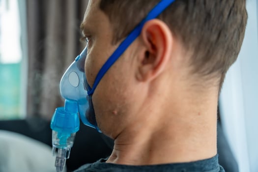 Unhealthy man wearing nebulizer mask in home. Health, medical equipment and people concept. High quality photo