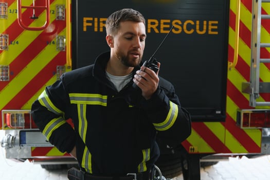 fireman in protective uniform standing near fire engine on station photo