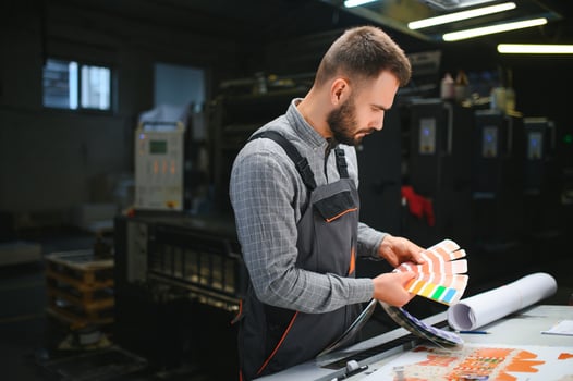 Print house worker controlling printing process quality and checking colors with magnifying glass photo