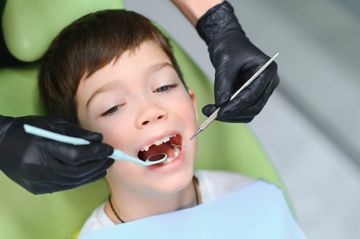 Dentist examining little boy's teeth in clinic photo