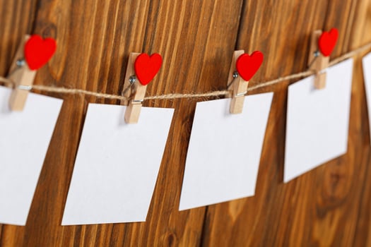 white pieces of paper on clothespins with a heart on a wooden background photo