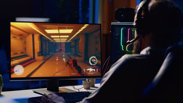 Man relaxing by playing futuristic science fiction videogame on PC at computer desk late at night. Gamer shooting enemies with lasers in online multiplayer first person shooter photo