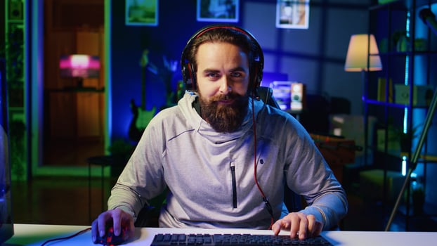Happy gamer talking with friends, celebrating after winning online competitive multiplayer tourney. Cheerful man playing videogames with internet teammates, feeling excited after being victorious photo
