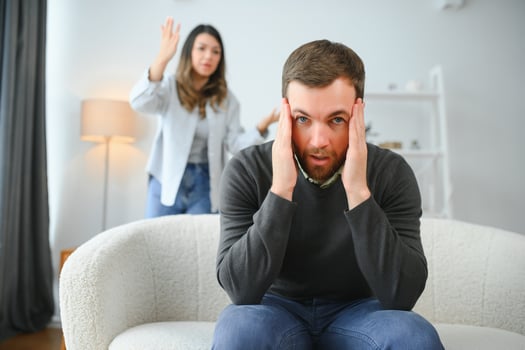 Family quarrel, man and woman sitting on sofa at home. angry woman yells at her husband photo