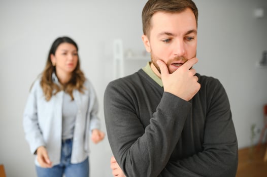 Couple arguing. Wife shouting to her desperate husband sitting on a couch in the living room at home photo