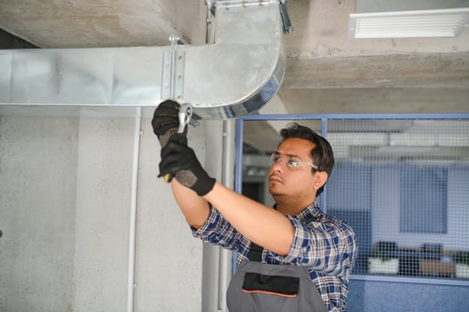 hvac indian worker install ducted pipe system for ventilation and air conditioning. copy space photo