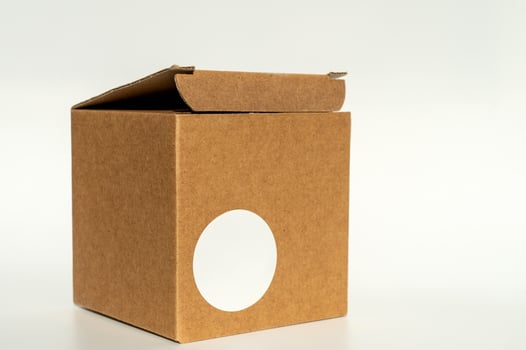 Brown cardboard box with circular white sticker on a neutral background. photo