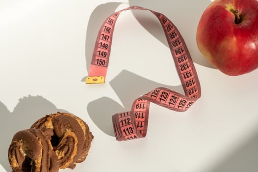 Measuring tape with cute emoji face on white background, apple and chocolate cookie shadow play photo