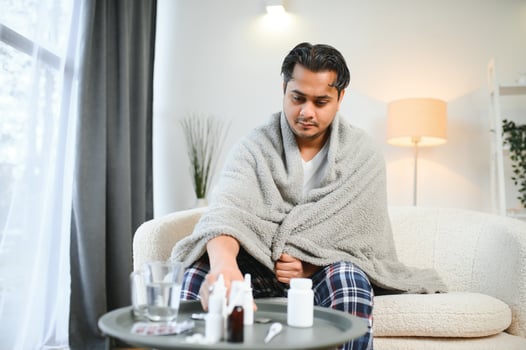 health, cold and people concept - sick young indian man in blanket having headache or fever at home photo