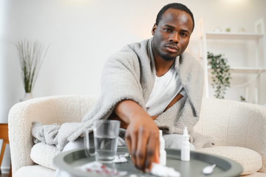 An African man sick with croup or a cold is covered with a blanket at home photo