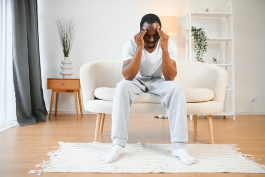 Upset african-american man squeezing head with hands, writhing in pain, suffering from headache at home, copy space photo