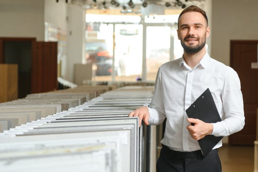 Portrait of a ceramic tile seller. The seller stands against the background of a large assortment of tiles photo