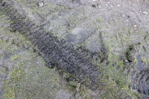 Wheel track on mud. Traces of a tractor or heavy off-road car on brown mud in wet meadow photo