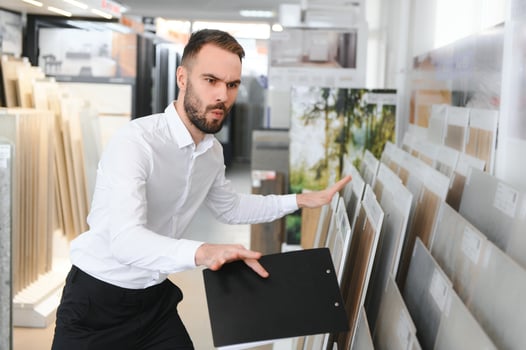 Portrait of a ceramic tile seller. The seller stands against the background of a large assortment of tiles photo