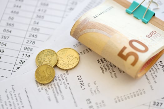 Heap of euro money bills in stationery clip on papers with calculations and receipts. Business and accounting concept photo