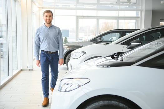 Young man, selling electric cars in the showroom. Concept of buying eco-friendly car for family photo