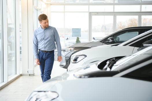 Young man buying first electric car in the showroom. Eco car sale concept photo