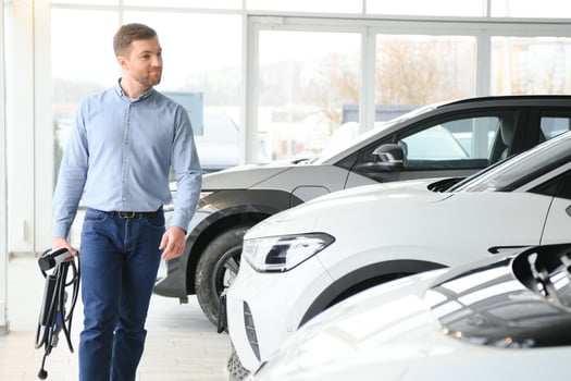 Young man, selling electric cars in the showroom. Concept of buying eco-friendly car for family photo