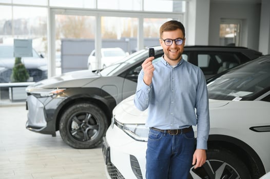 Concept of buying electric vehicle. Handsome business man stands near electric car at dealership photo