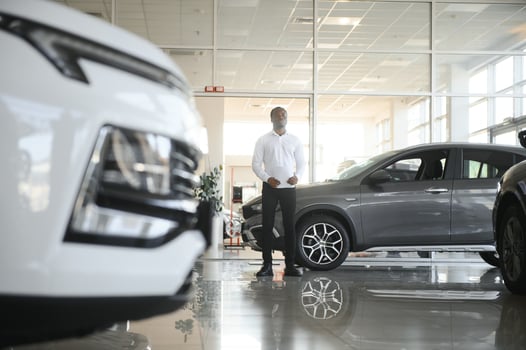 Portrait Of Handsome African American Salesman At Workplace In Car Showroom photo