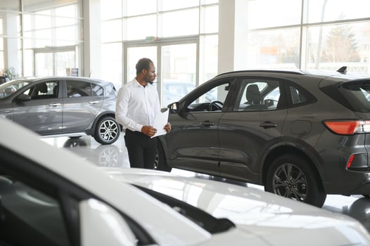 Portrait Of Handsome African American Salesman At Workplace In Car Showroom photo