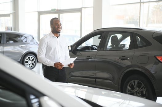 young african american car dealership principal standing in vehicle showroom photo