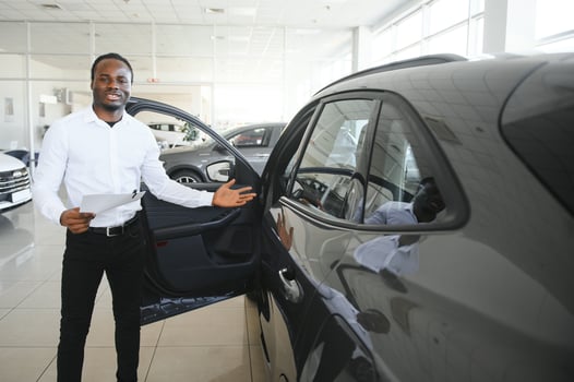 Portrait Of Handsome African American Salesman At Workplace In Car Showroom photo