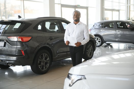 Portrait Of Handsome African American Salesman At Workplace In Car Showroom photo