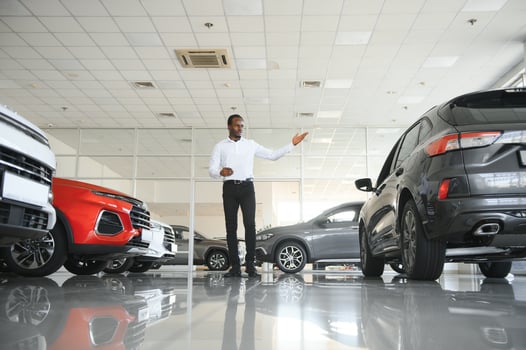 Cars Dealership Concept. Auto Seller Afro Man Standing In Automobile Center photo