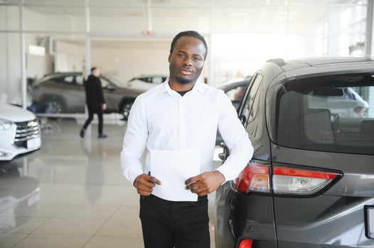 young african american car dealership principal standing in vehicle showroom photo