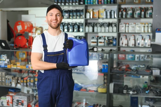 seller man with canister of motor oil in auto store photo