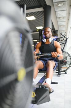 Motivated young black sportsman having workout on rowing machine photo