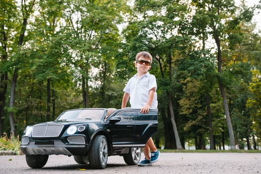 Cute boy in riding a black electric car in the park. Funny boy rides on a toy electric car. Copy space. photo