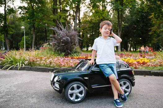 Cute boy in riding a black electric car in the park. Funny boy rides on a toy electric car. Copy space. photo